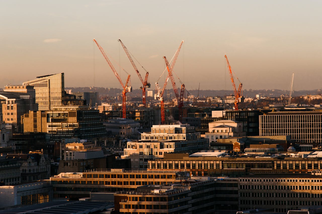 Skyline of London with construction cranes at sunset, showcasing modern architecture and urban development.